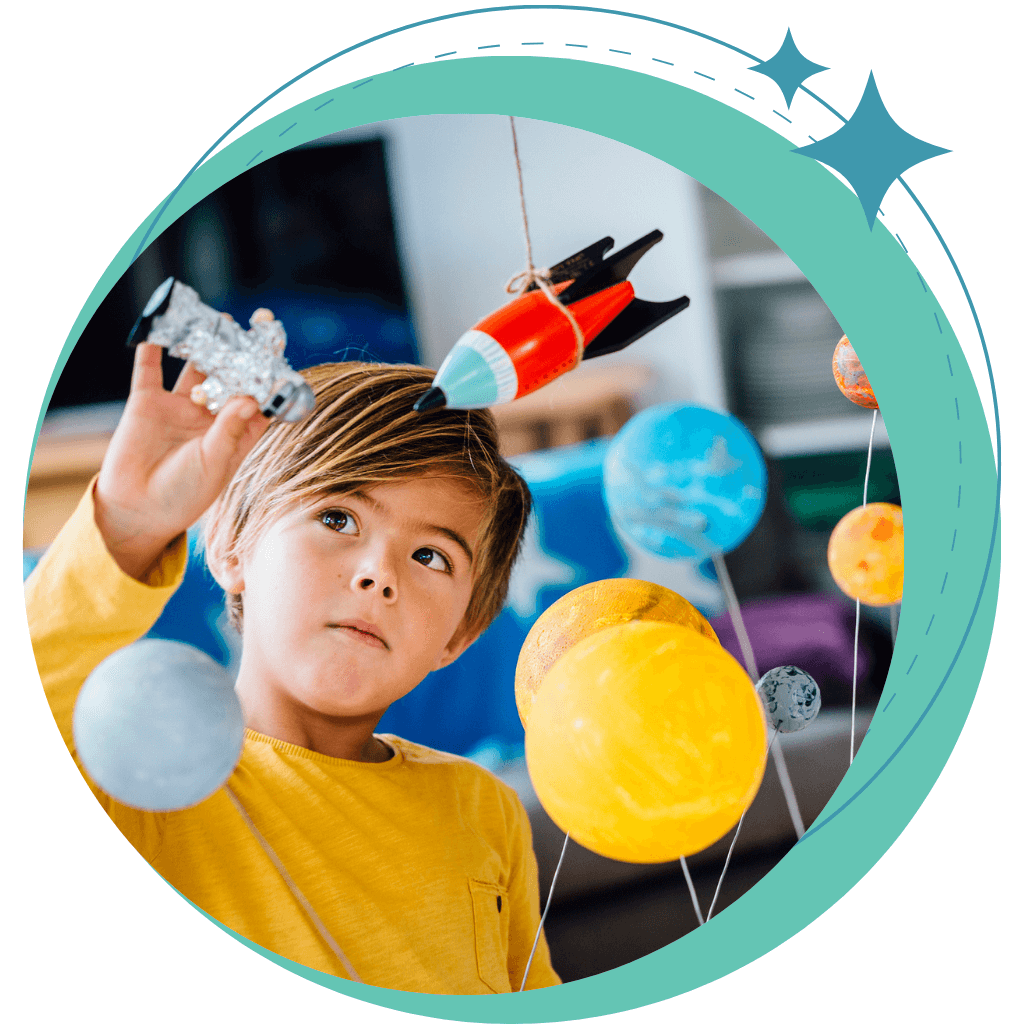 Caucasian boy with yellow top playing with rockets and planets
