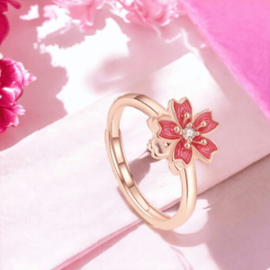 Cherry blossom ring for fidgeting next to pink flowers on a pink surface
