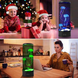 Two toddlers looking at a jellyfish light on the floor and a woman working on the computer with a jellyfish lamp on the table
