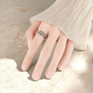 Woman's hand wearing a sterling silver fidget ring on a sandstone surface
