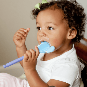 Afro american toddler girl eating yogurt with Ark's mouse tip for Z-Vibe feeding therapy tool