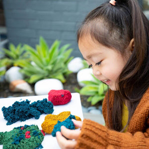 Asian girl playing with Playfoam® Naturals by Educational Insights at a white table