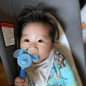 Asian infant in a car seat munching on a Mouse tip attached to a Z-Vibe
