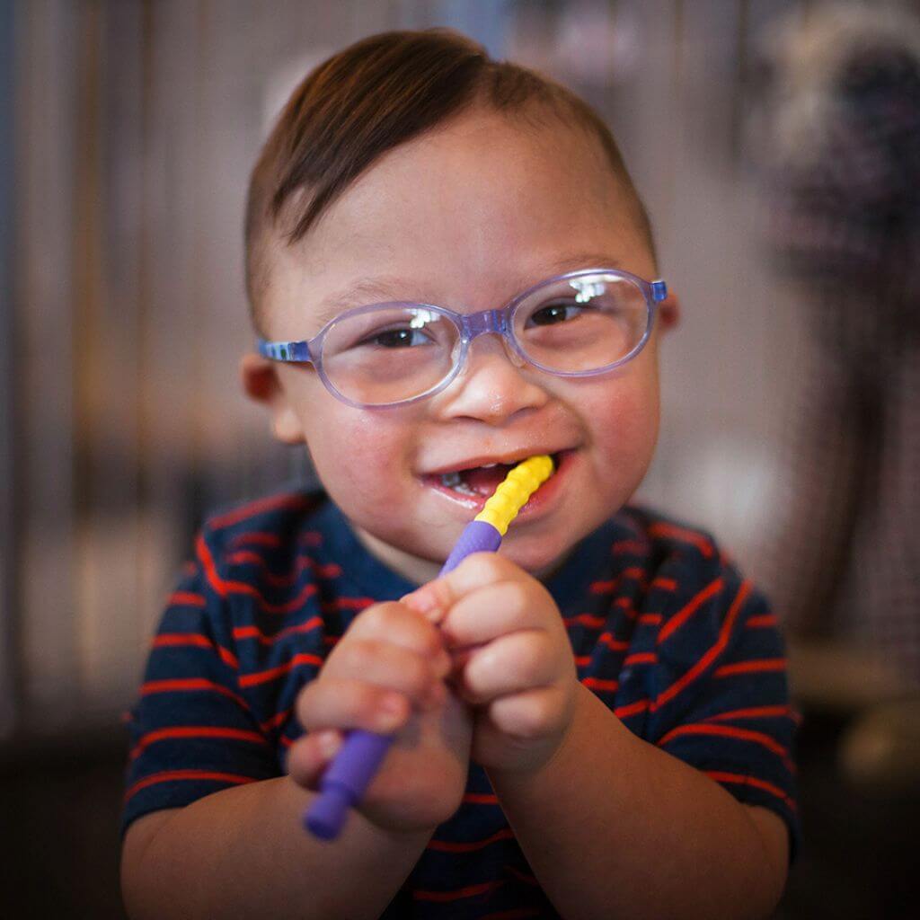 Autistic toddler chewing at a yellow textured Ark&#39;s Z-Vibe Bite-n-Chew Tip XL 