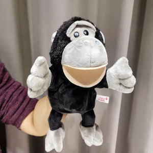 Baby chimpanzee open mouth hand puppet on woman's hand with a grey curtain in background