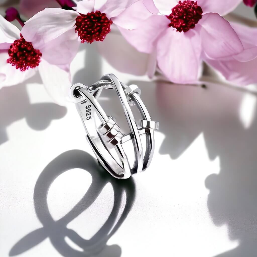 Beaded silver fidget ring next to pink flowers on white background