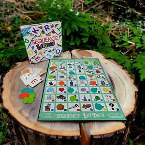 Box and contents of the Sequence Letters Board Game on a stump on grassy background