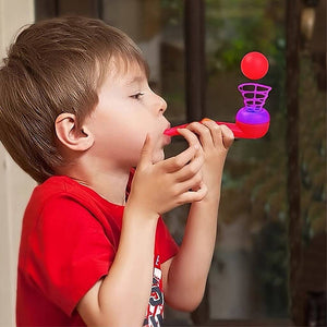 Boy blowing into a magic ball blow pipe and keeping the ball in the air