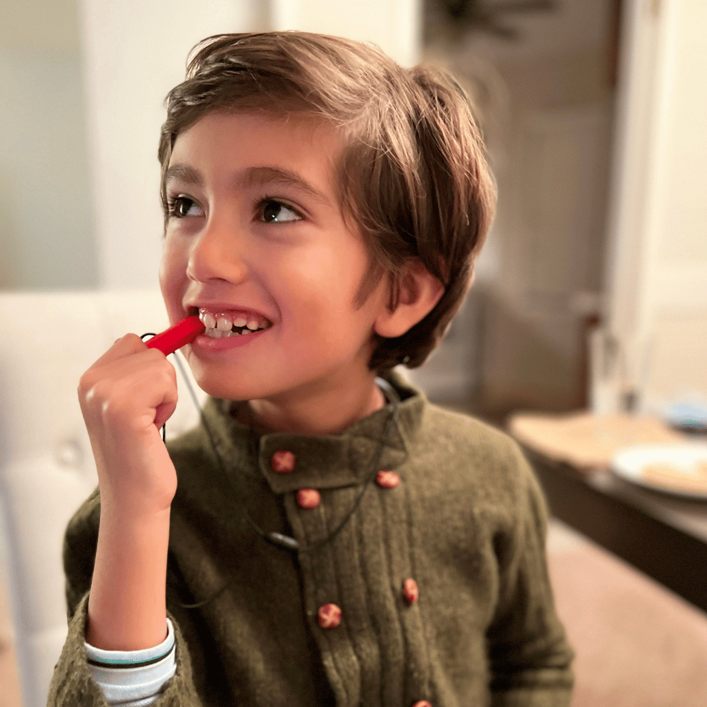 Boy chewing a red Ark Krypto Bite necklace