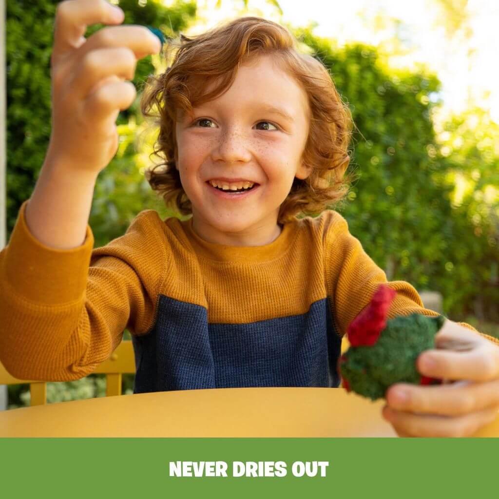 Boy with curly ginger hair playing with green Playfoam Naturals Shape & Learn Letters & Numbers at a yellow table