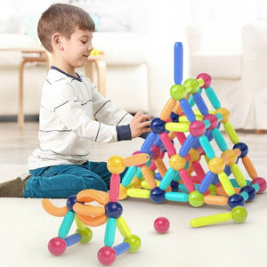 Boy playing with magnetic toys balls and rods on the floor