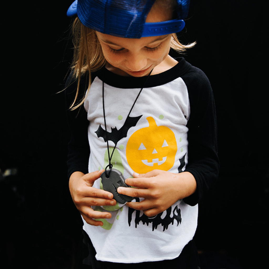 Boy wearing a T Rex chew necklace by Ark