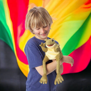 Caucasian boy carying a frog puppet from Folkmanis in his arms on colored background