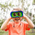 Caucasian boy in orange t-shirt looking through GeoSafari Kidnoculars by Educational Insights in a park
