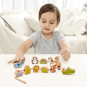 Caucasian boy playing with wooden lacing blocks zoo at a table