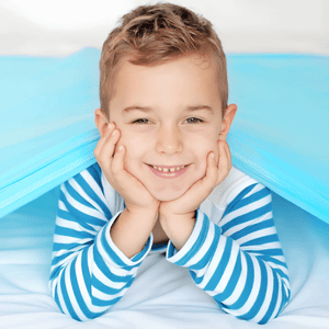 Caucasian boy with striped top in bed under a blue compression sheet