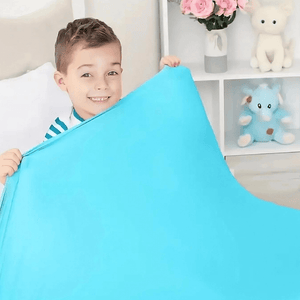 Caucasian boy with striped top in bed smiling under a blue sensory sheet