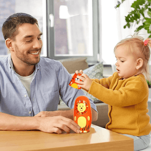 Caucasian father and daughter playing with a lion babushka doll at a table