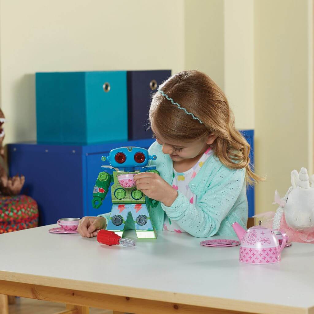 Caucasian girl feeding Design-drill-robot tea from a cup with blue furniture on the background
