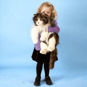 Caucasian girl holding a cat ragdoll puppet from Folkmanis on blue background