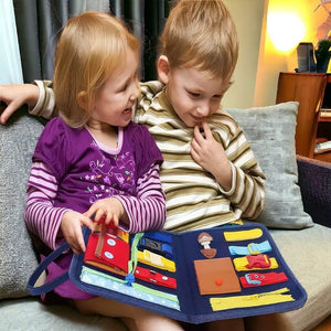 Caucasian toddler boy and girl playing with a busy book on a sofa in Australia