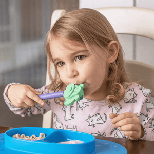 Caucasian toddler girl at a table licking a dog tip for Z-Vibe