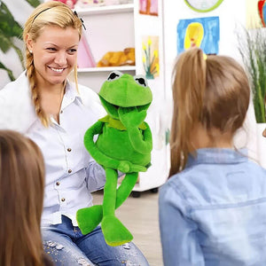 Caucasian woman holding a kermit frog hand puppet in front of children