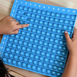 Child's hands playing with a pop it multiplication chart