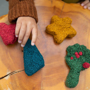 Child's hand making shapes with layfoam® Naturals by Educational Insights at a wooden table