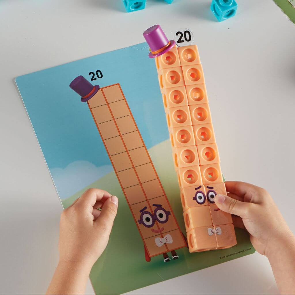 Child's hands building number twenty numberblocks mathlink cubes inspired by the TV on a white table