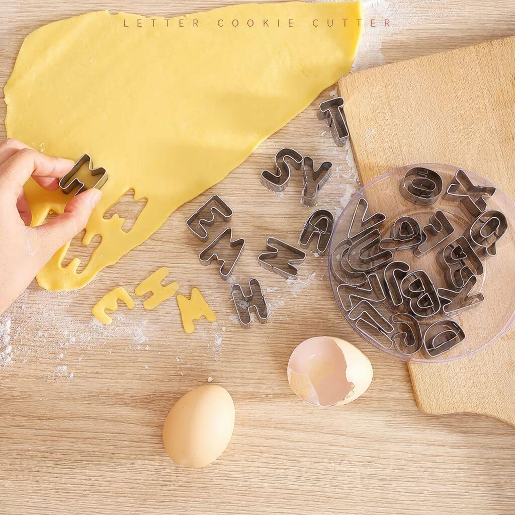 Cookie cutters letters next to dough and eggs