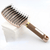 Detangling hair brush gold on a stack of white paper