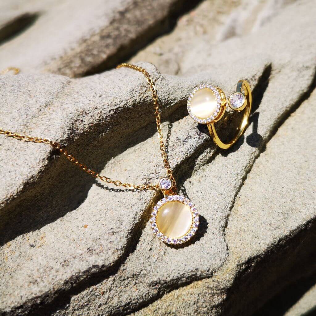 Fidget jewellery necklace and ring with opal spinning top on a grey rock