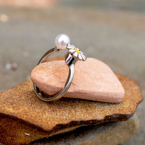 Fidget ring with flower and pearl on a pink rock close up