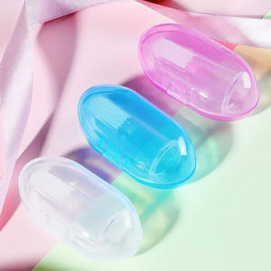 Finger toothbrushes in blue, ping and white cases on a pink and green surface