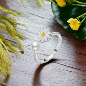 Flower pearl ring for fidgeting on a wooden table next to green and yellow plants