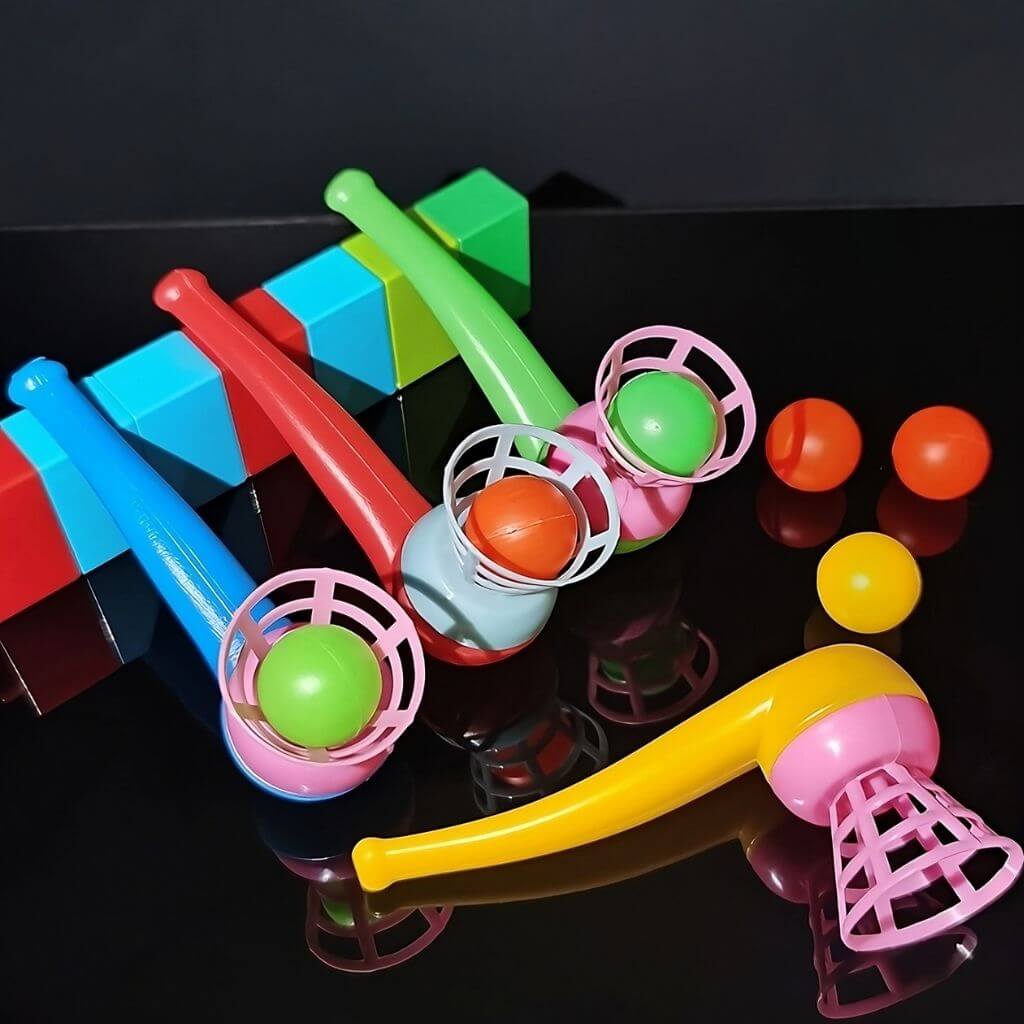 Four multi colored magic ball blowing pipes on a black mirrored surface