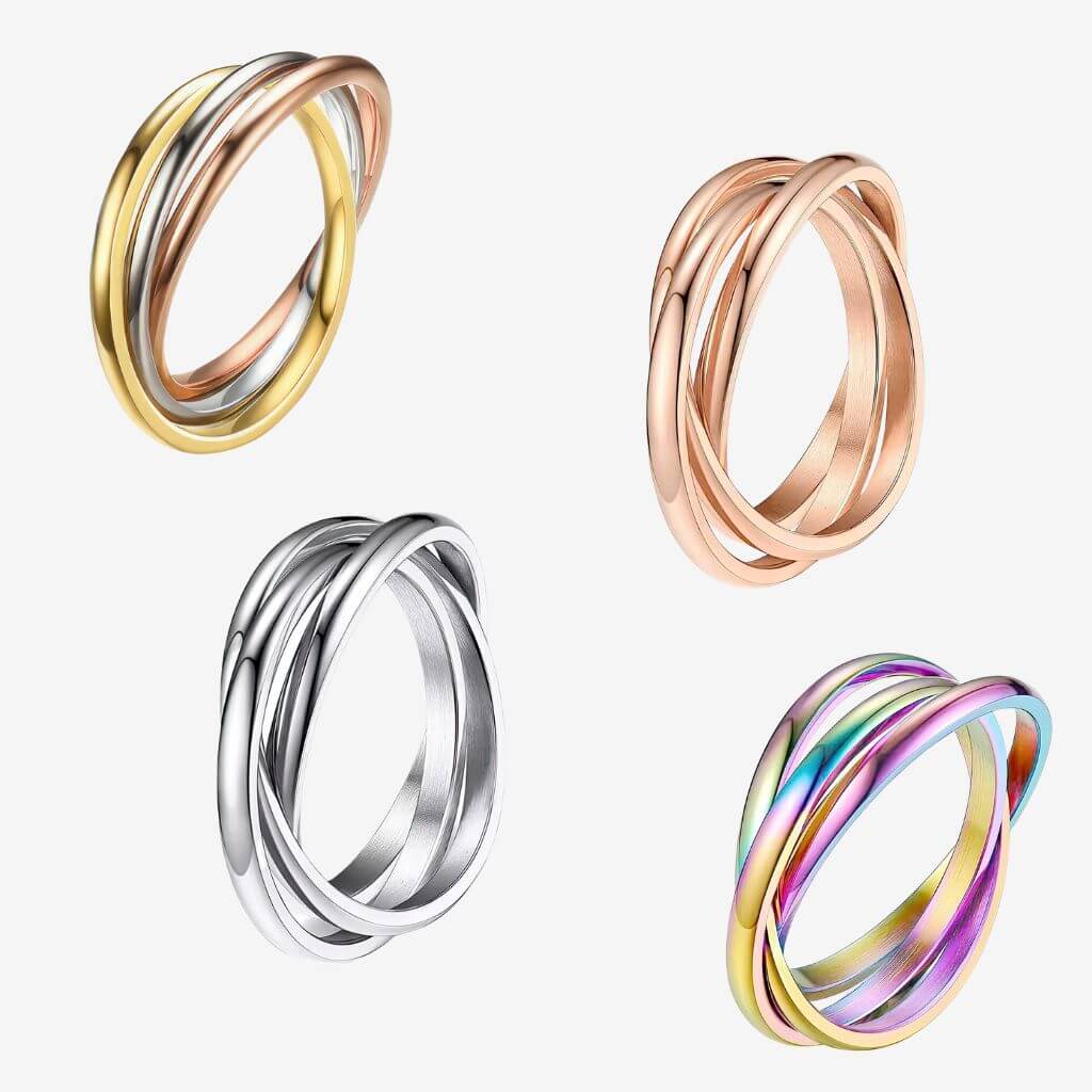 Four stainless steel fidget rings in different colors on a white background
