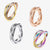 Four stainless steel fidget rings in different colors on a white background
