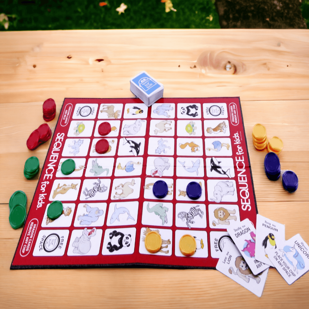 Game board, cards and chips from Sequence for Kids Game on a wooden table