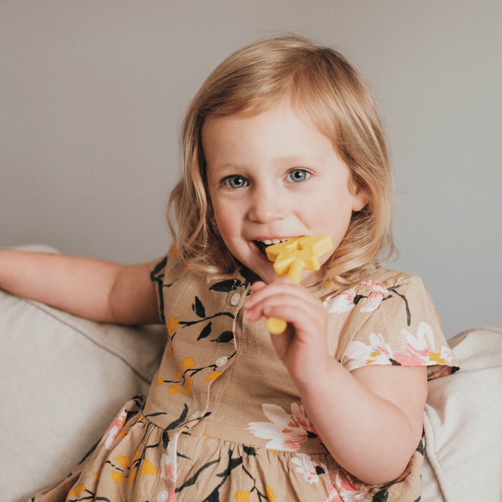 Girl chewing  an Ark Fairy Princess Star Wand Chewy