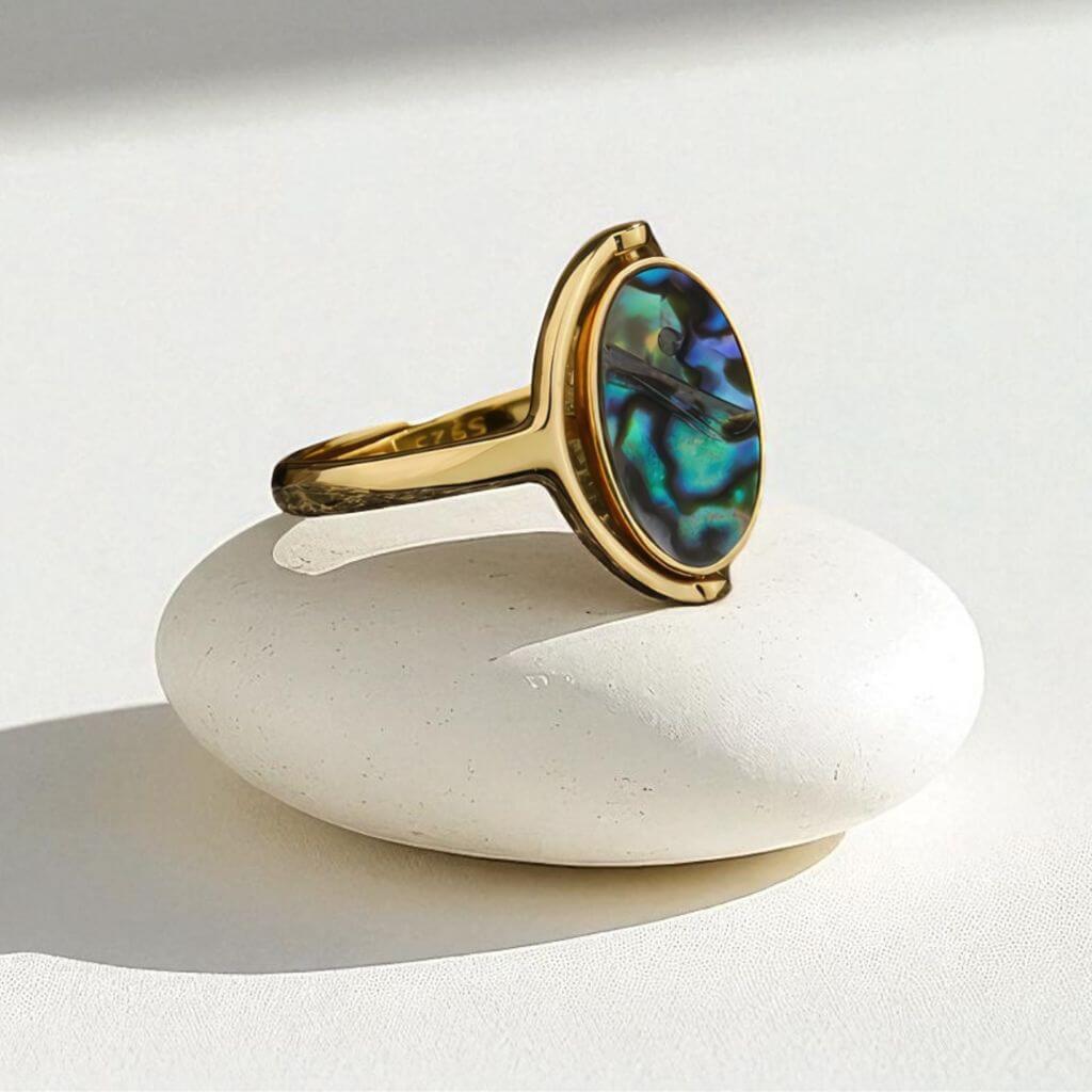 Gold abalone rotating ring on a white stone