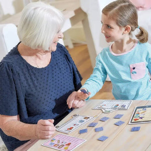 Grandmother and granddaughter playing Shopping List Game by Orchard Toys