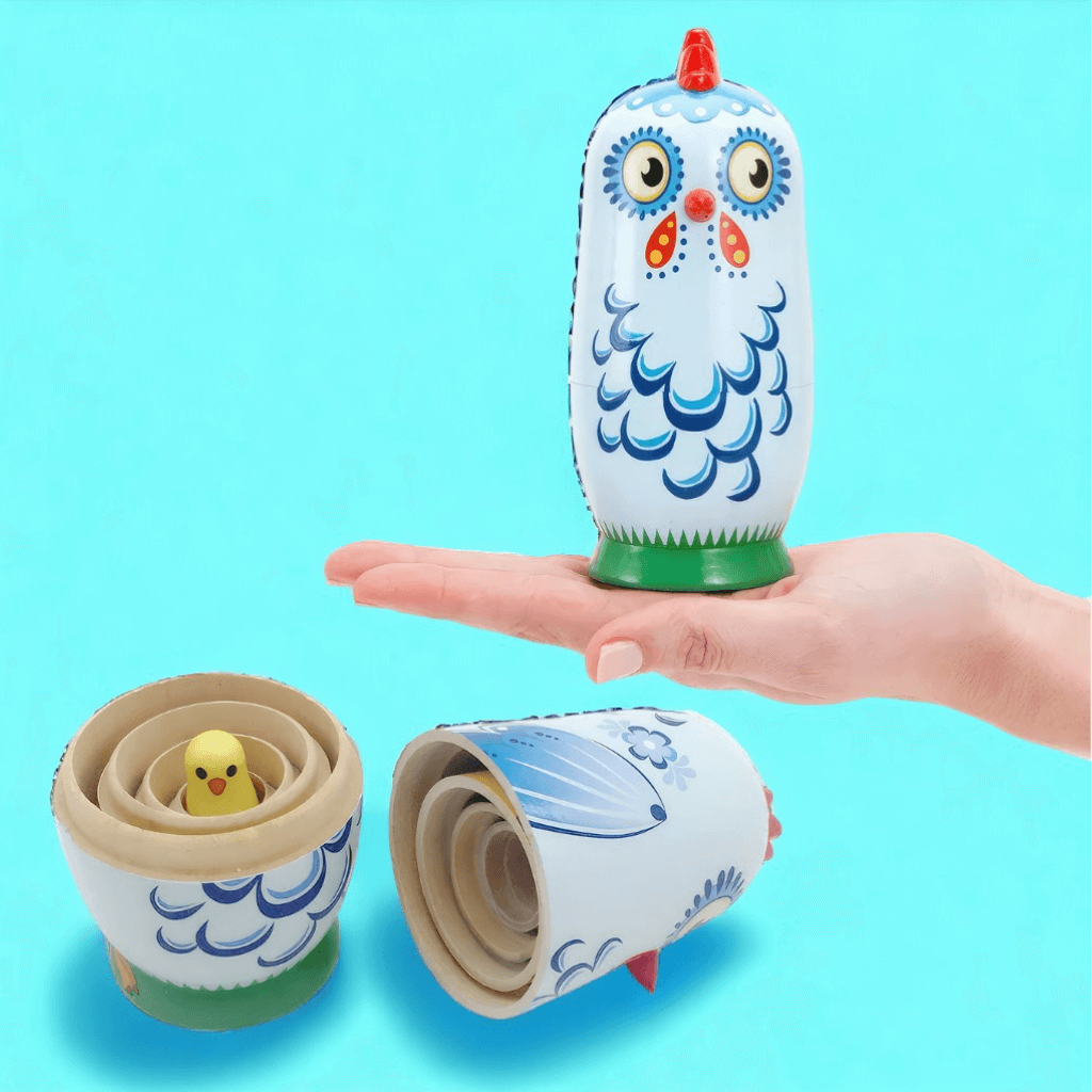 Hand holding a babushka doll on blue background