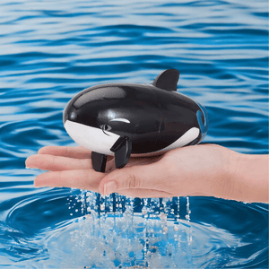 Hand holding a whale babushka doll on water background