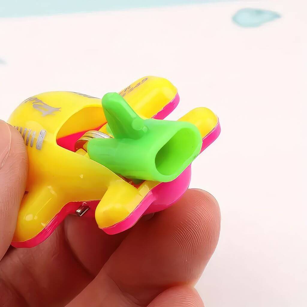Hand holding a yellow airplane whistle