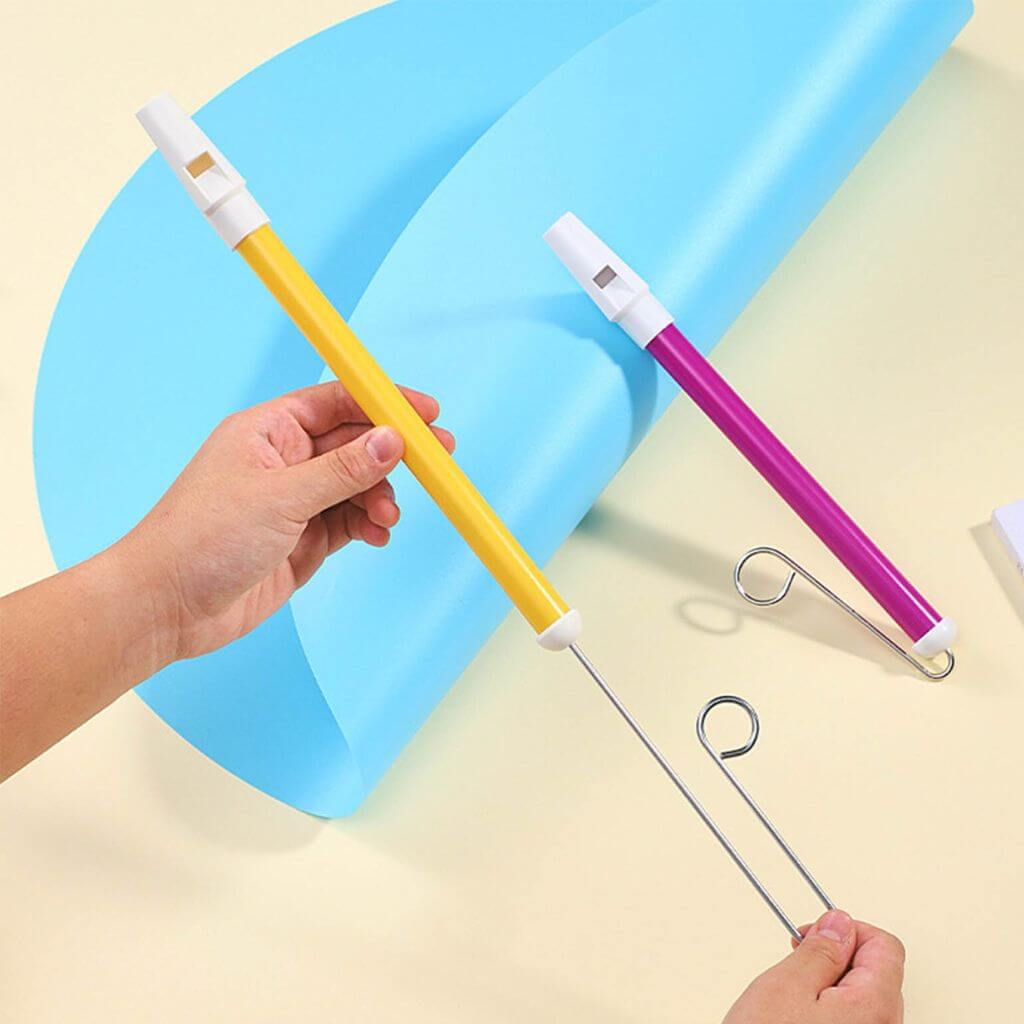 Hand holding a yellow slide whistle and another hand pulling the slide