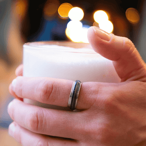 Hand wearing a mood ring holding a white candle
