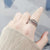 Hand wearing a silver beaded ring with a blurred background