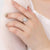 Hand wearing a silver ring with an opal center on a light background